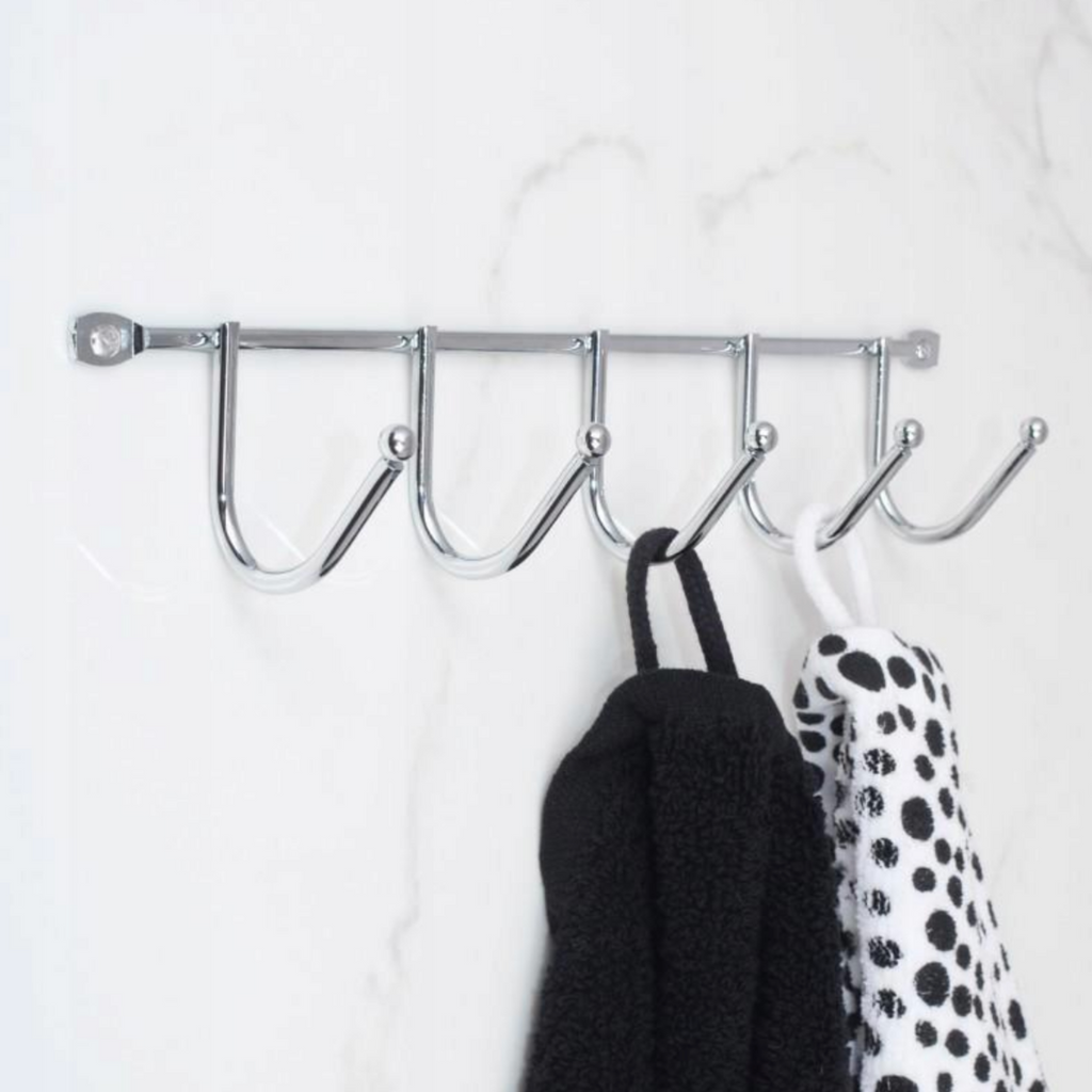 Polished stainless steel rail with six hooks mounted on a bathroom wall