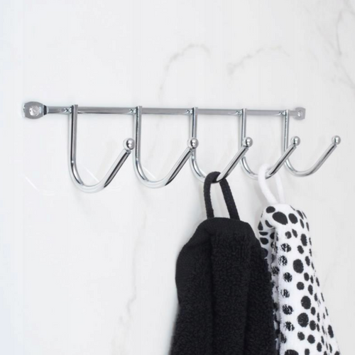 Polished stainless steel rail with six hooks mounted on a bathroom wall