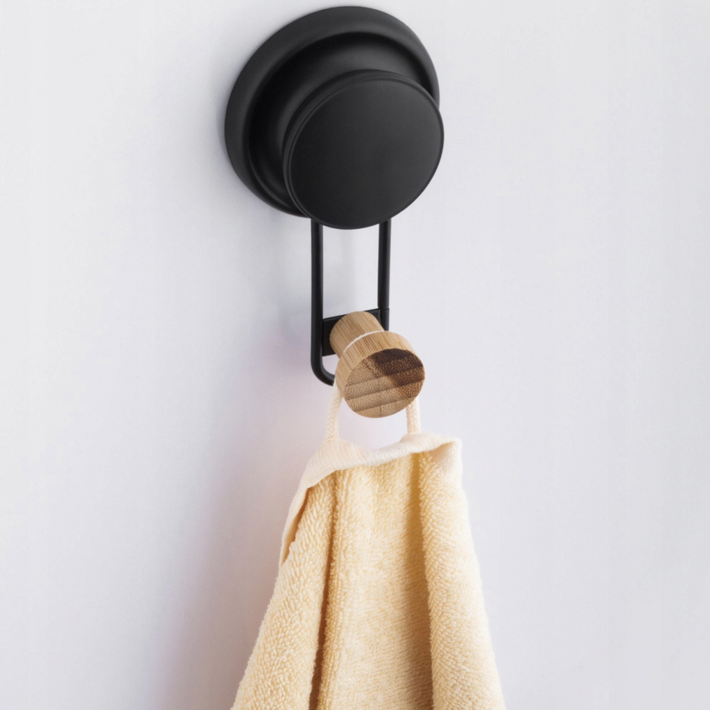 Matte black towel hook with a bamboo tip mounted on a bathroom tile