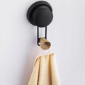 Matte black towel hook with a bamboo tip mounted on a bathroom tile