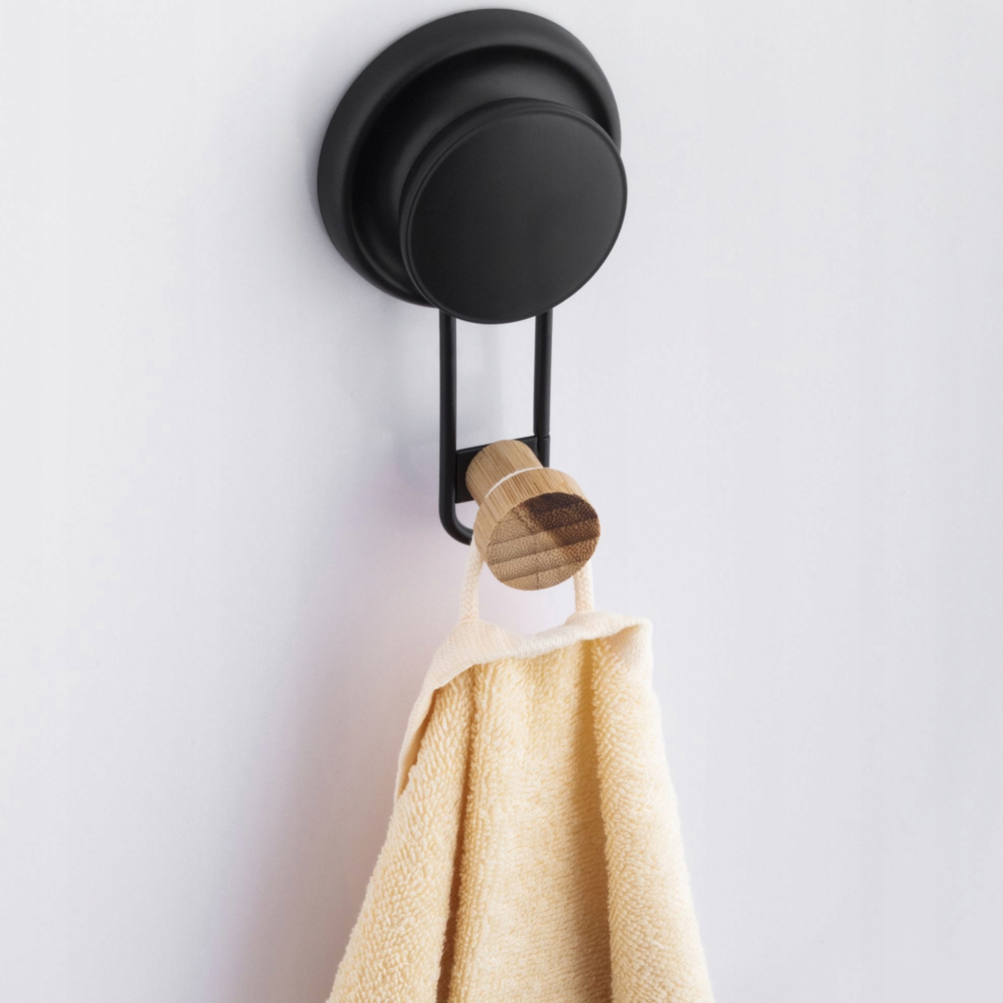 Matte black towel hook with a bamboo tip mounted on a bathroom tile