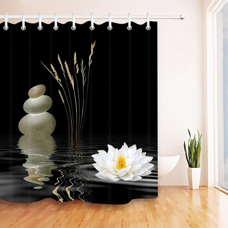 Pale pebbles reeds and a white lotus at the foot of a deep black panel
