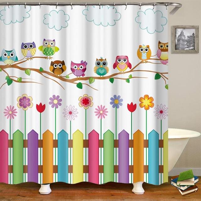 Row of colorful owls perched on a branch above flowers and a fence