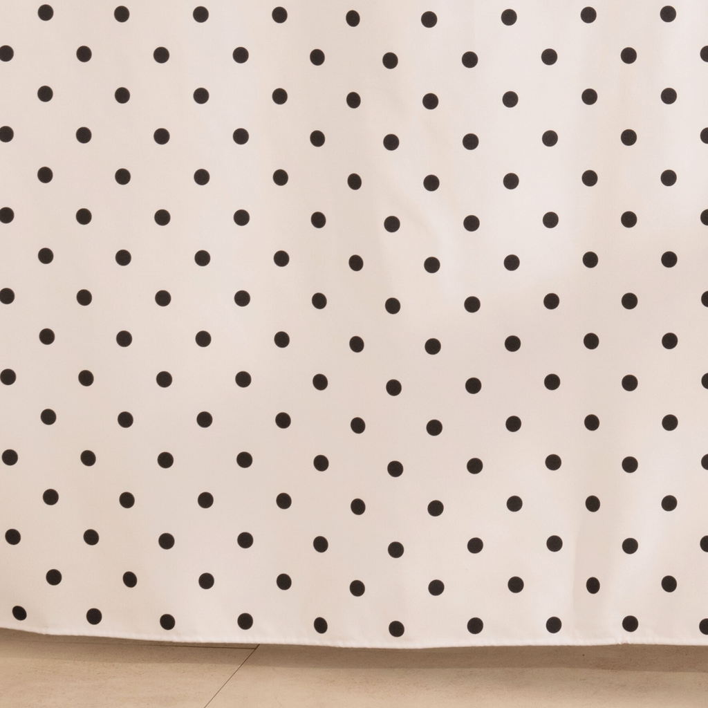 Full length dotted beige curtain hanging beside a glass screen