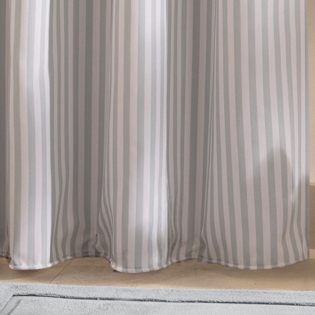 Full length blue striped curtain hanging beside a white bathtub