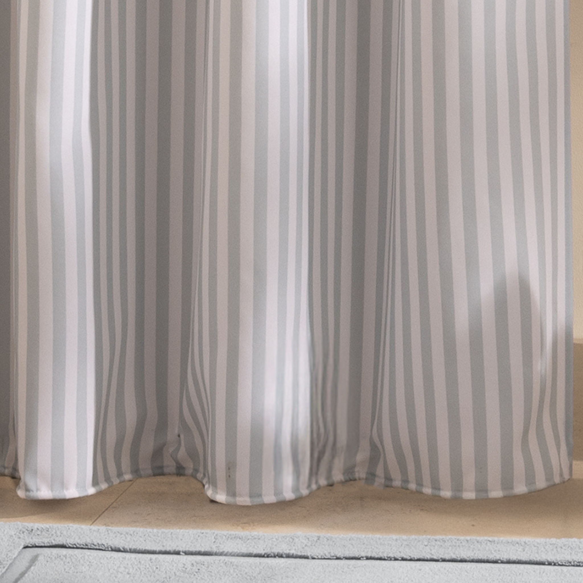 Full length blue striped curtain hanging beside a white bathtub