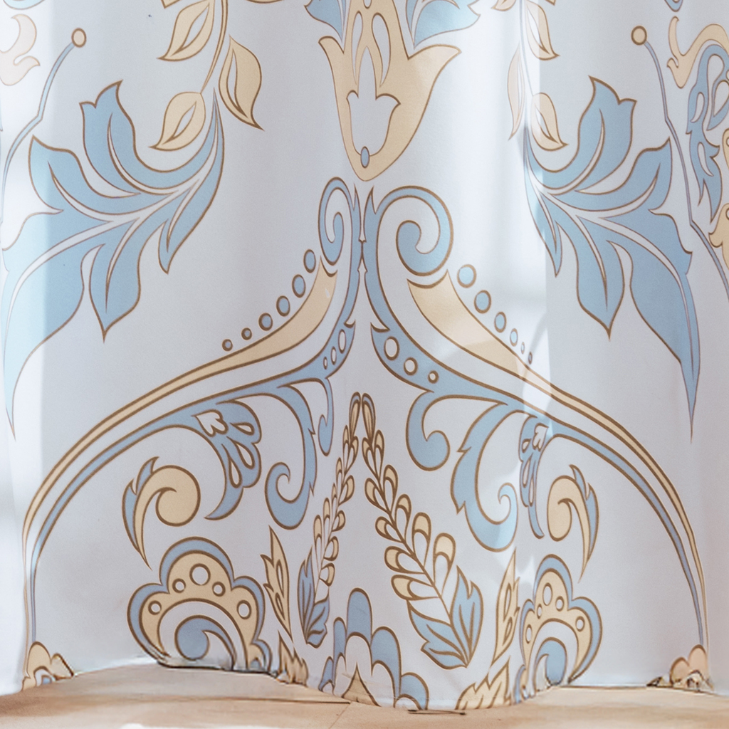 Full length blue toile curtain hanging beside a white bathtub