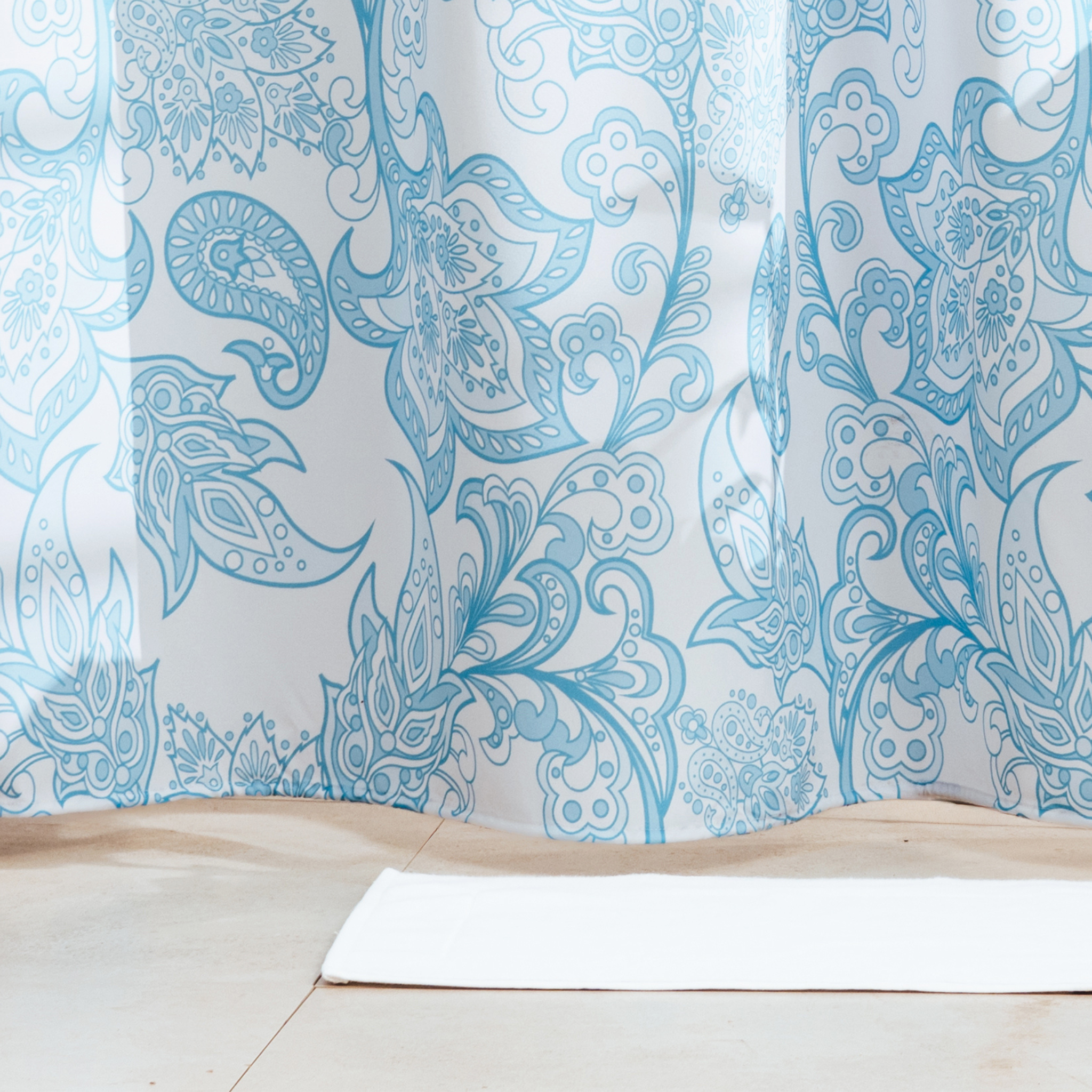 Full length dusty blue floral curtain hanging beside a bathtub