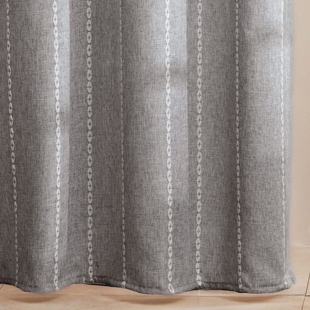 Full length grey curtain hanging beside a glass shower screen