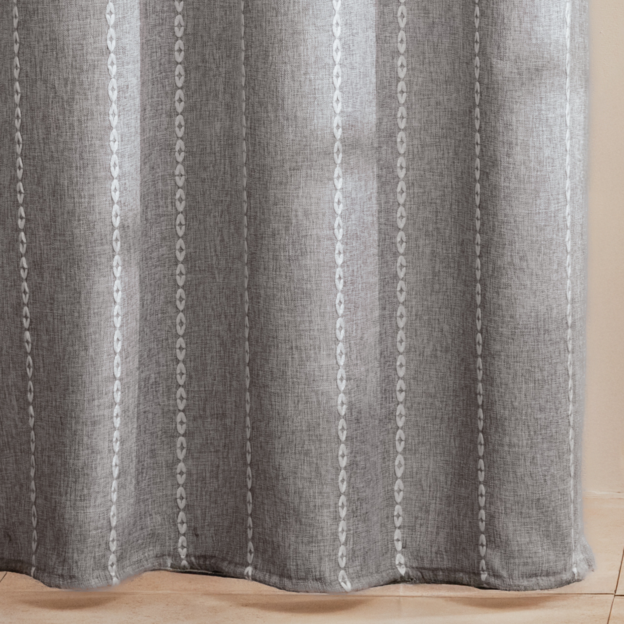 Full length grey curtain hanging beside a glass shower screen