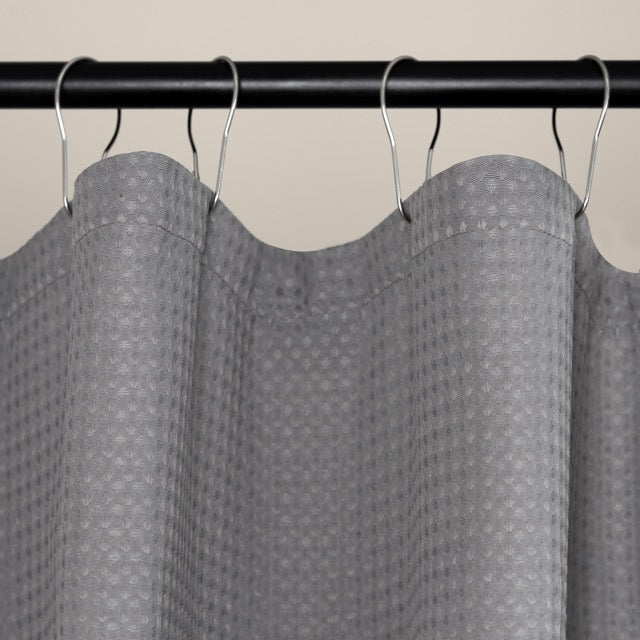 Grey waffle curtain styled beside a bathtub with warm daylight