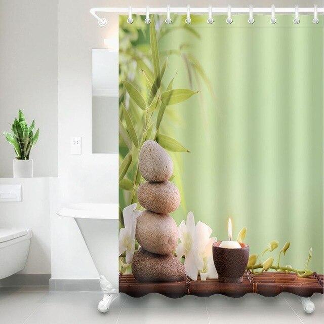 Stacked beige stones bamboo and a candle beside a plain sage green half