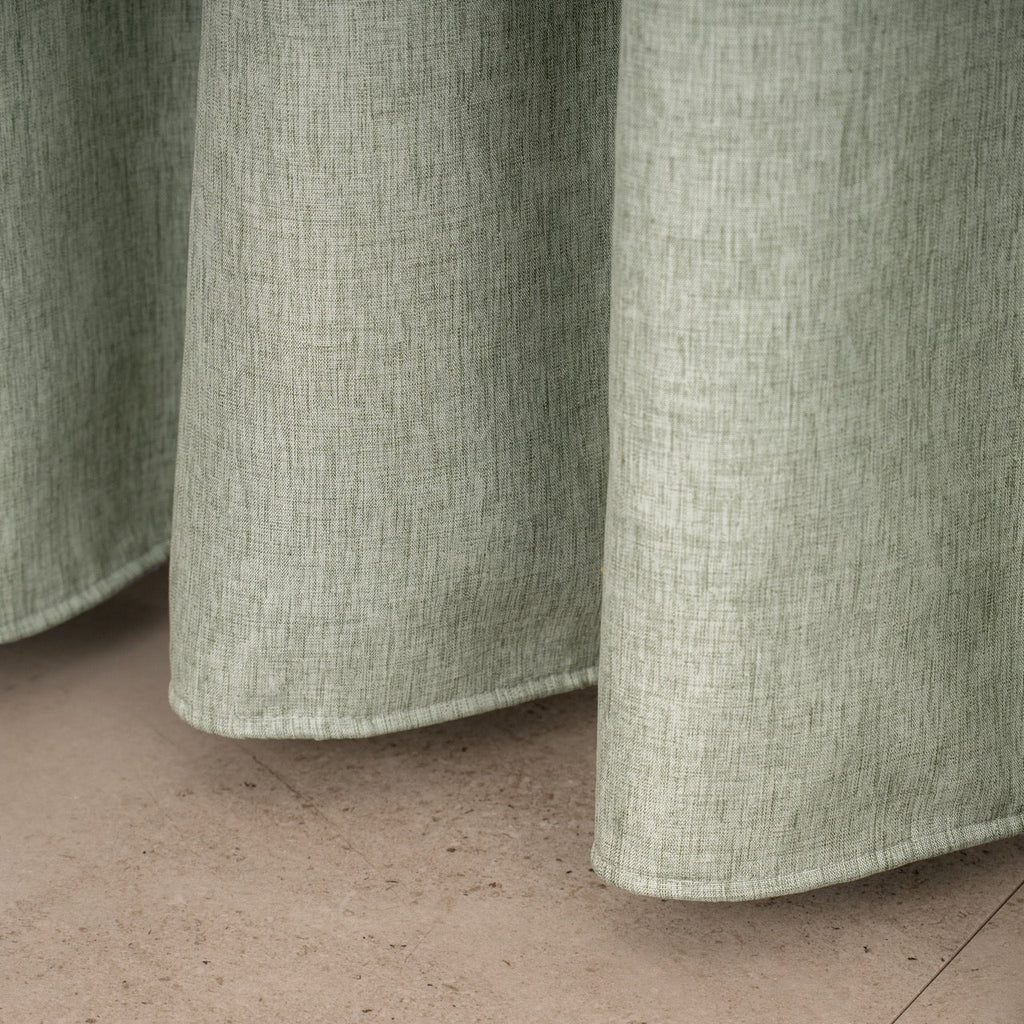 Full length sage linen curtain hanging beside a glass shower screen