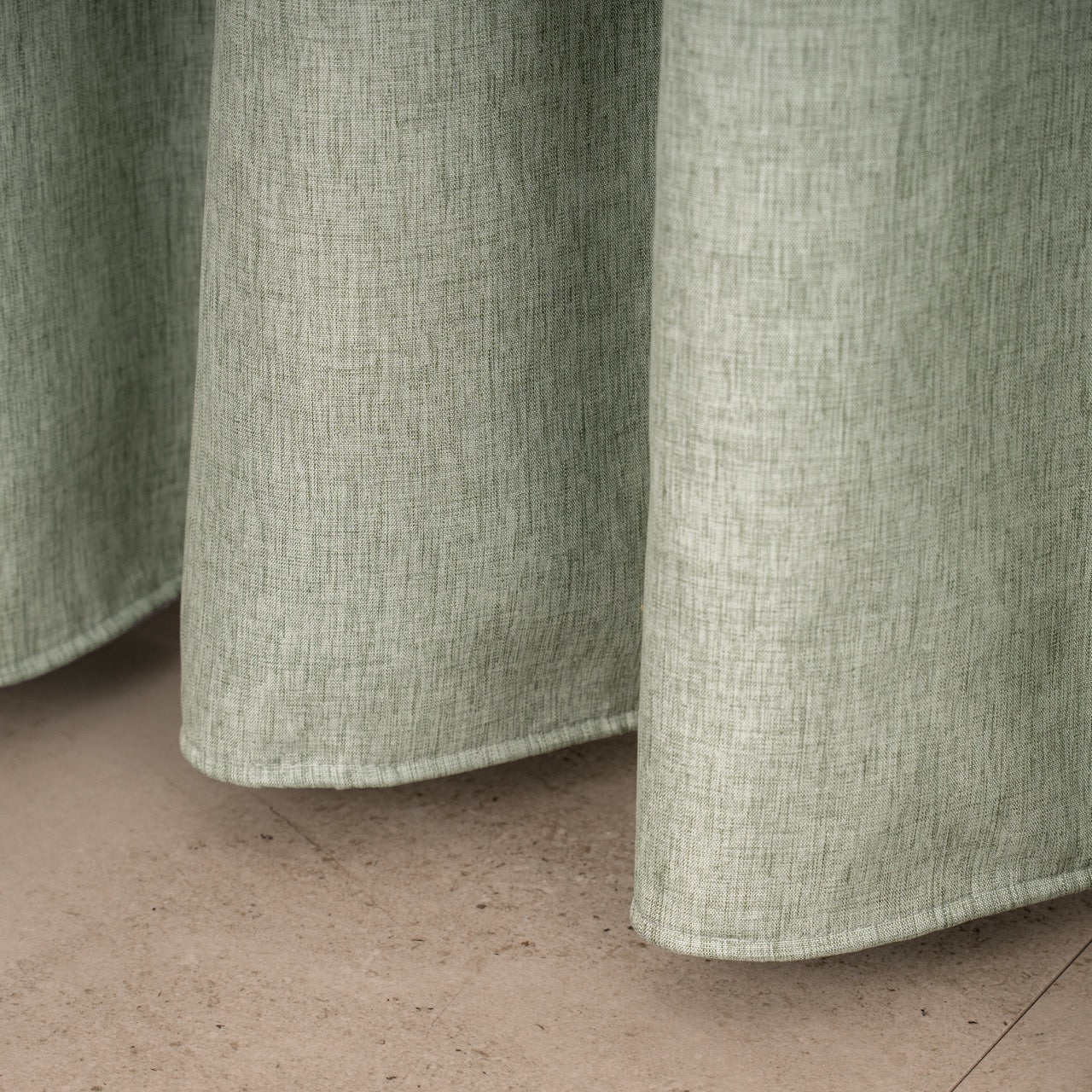 Full length sage linen curtain hanging beside a glass shower screen