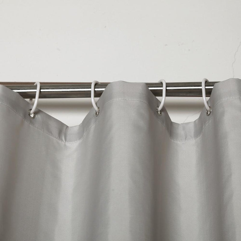 Full length greige curtain hanging straight beside a white bathtub