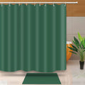 Solid deep emerald green curtain hanging with a matching dark green bath mat