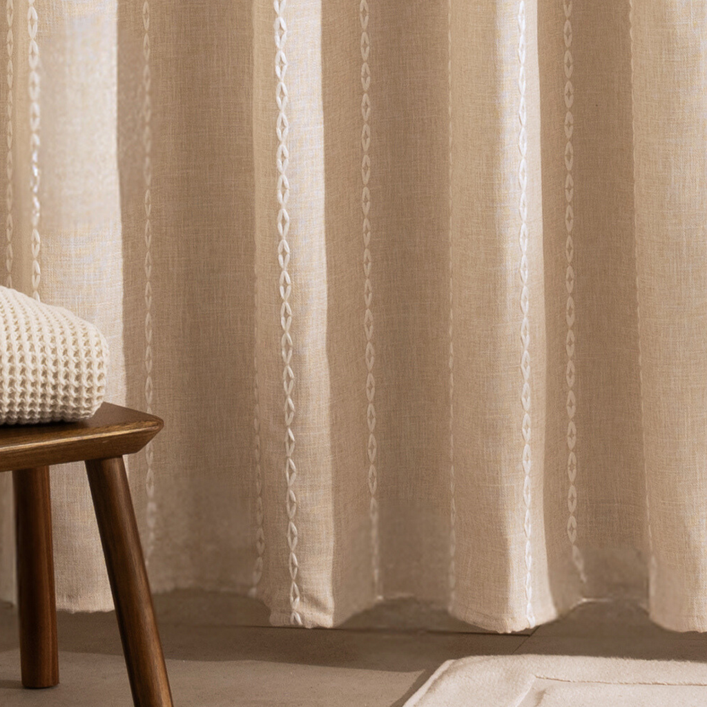Full length natural beige curtain hanging beside a glass screen
