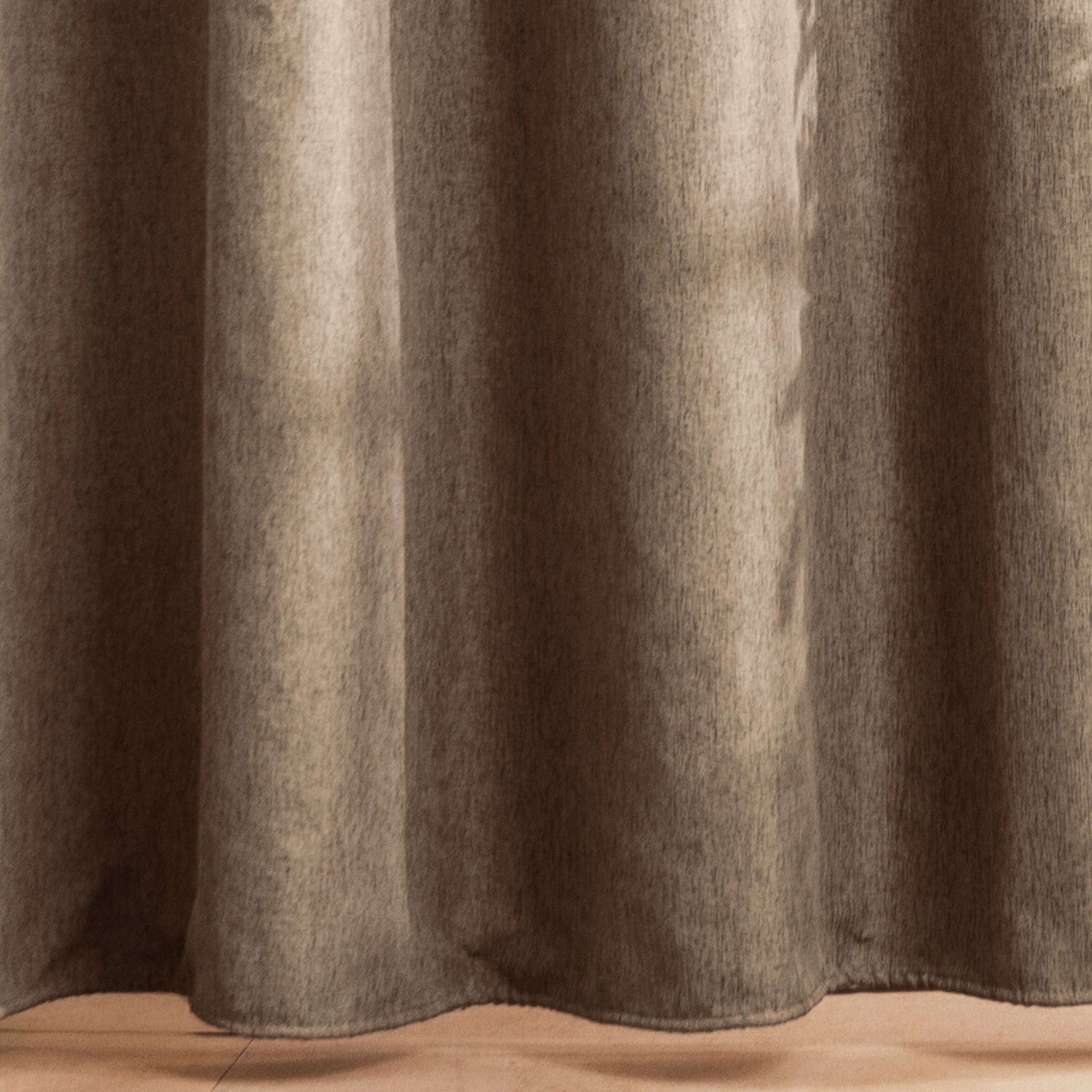 Full length greige curtain hanging beside a glass shower screen