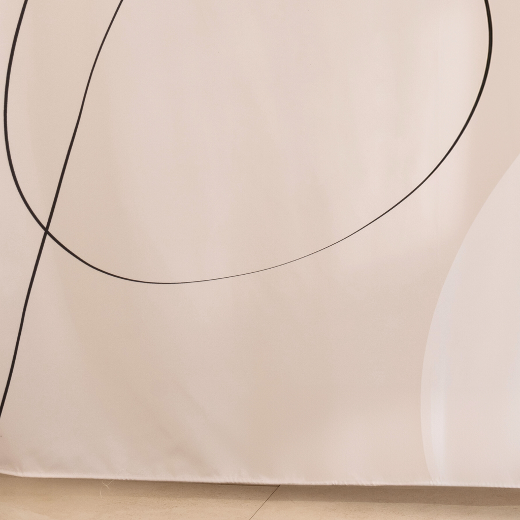 Full length off white curtain hanging beside a glass shower screen