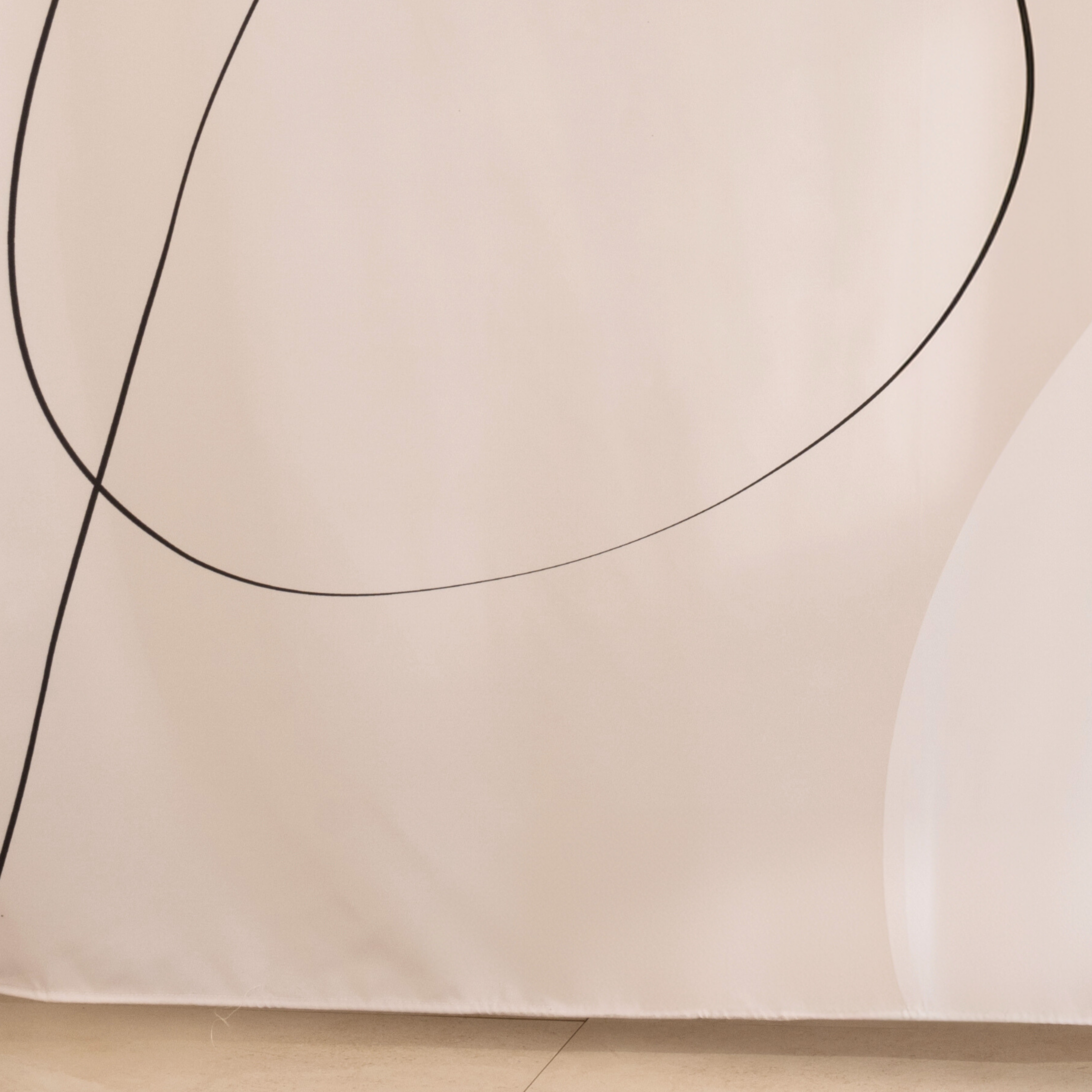 Full length off white curtain hanging beside a glass shower screen