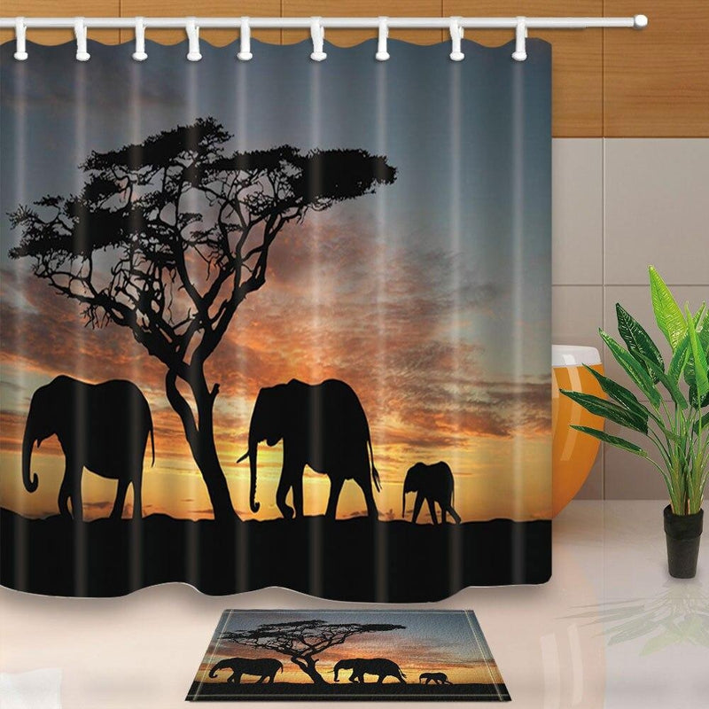 Black silhouettes of an acacia and three elephants against an orange sunset sky