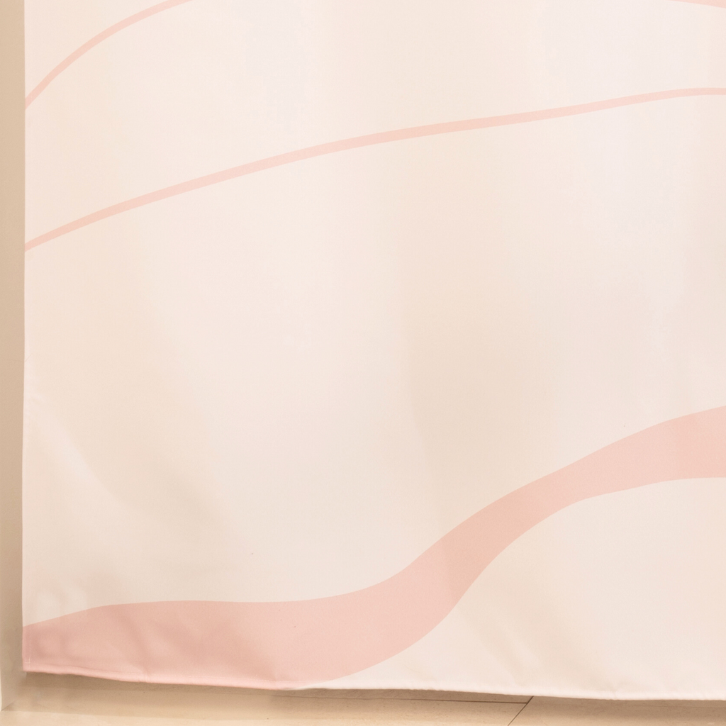 Full length pale pink curtain hanging beside a glass shower screen