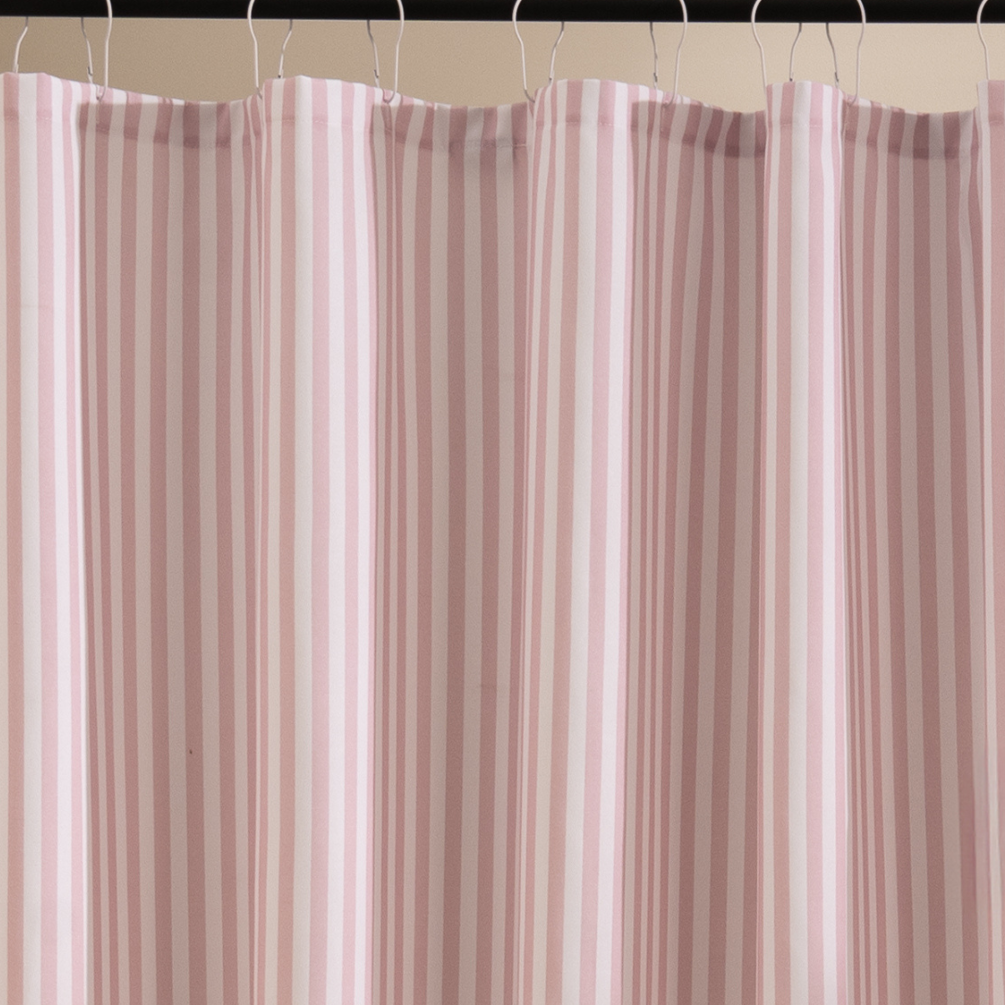 Full length pink striped curtain hanging beside a white bathtub