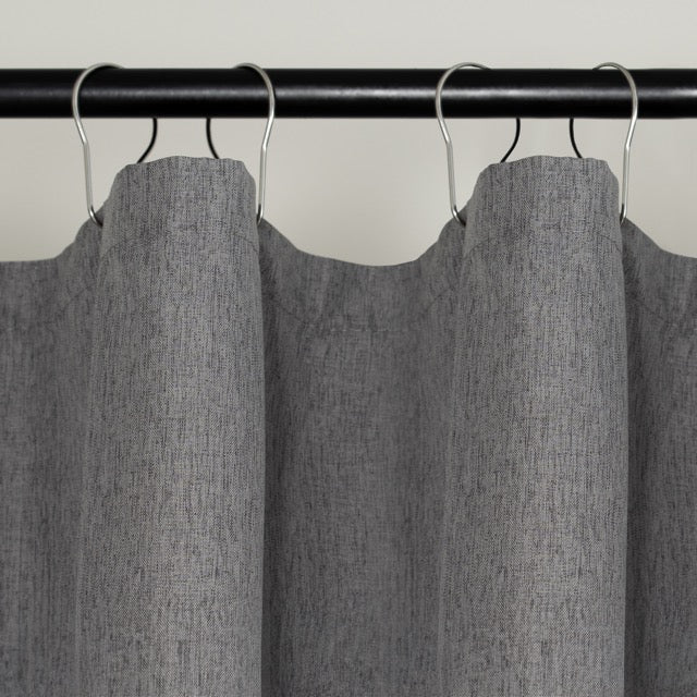 Full length plain grey curtain hanging beside a glass shower screen