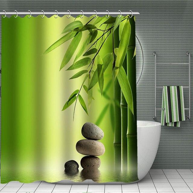 Bamboo stems beside three stacked grey pebbles on a soft green gradient