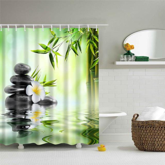 Black stacked stones and a white flower before green bamboo reflected in water