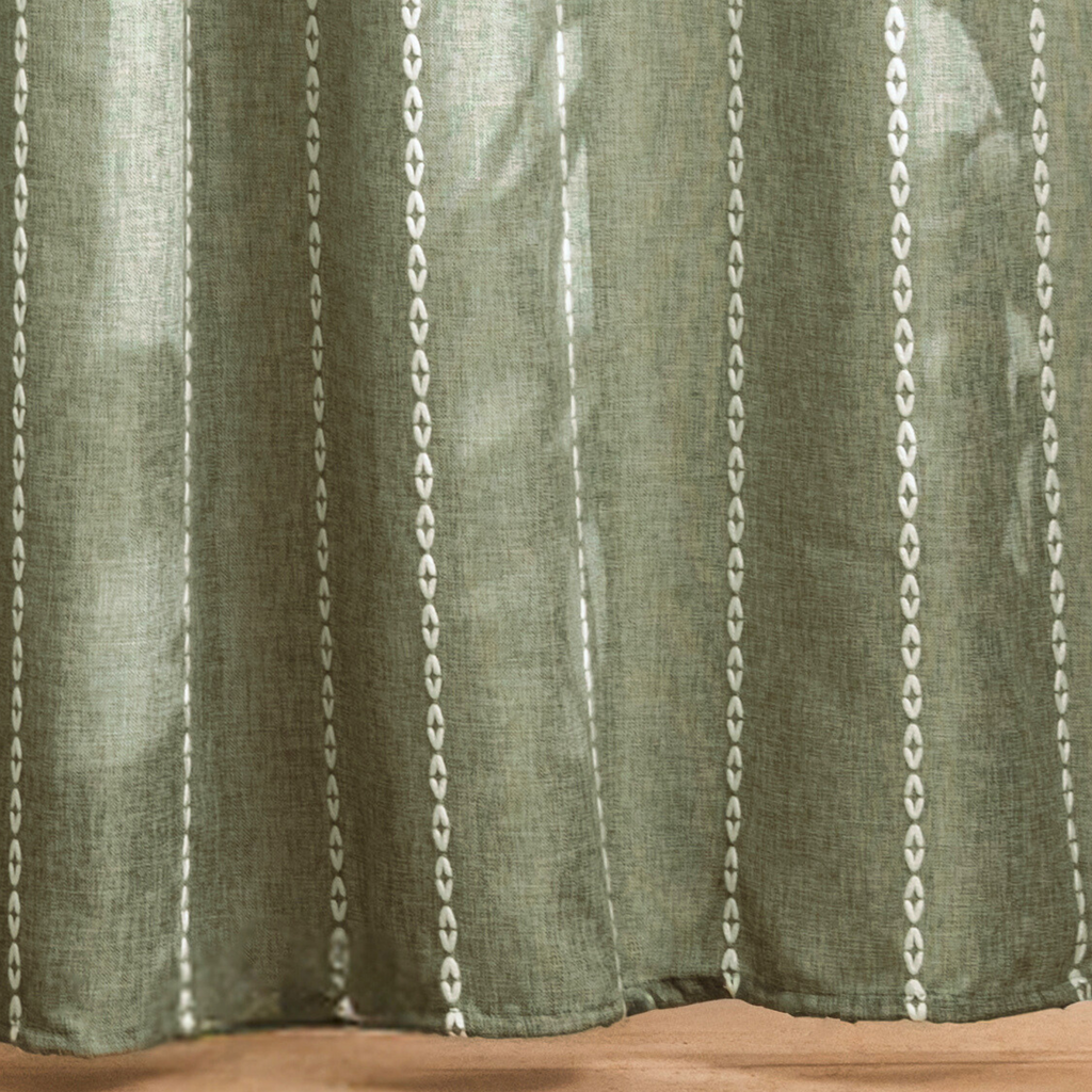 Full length sage green curtain hanging beside a white bathtub