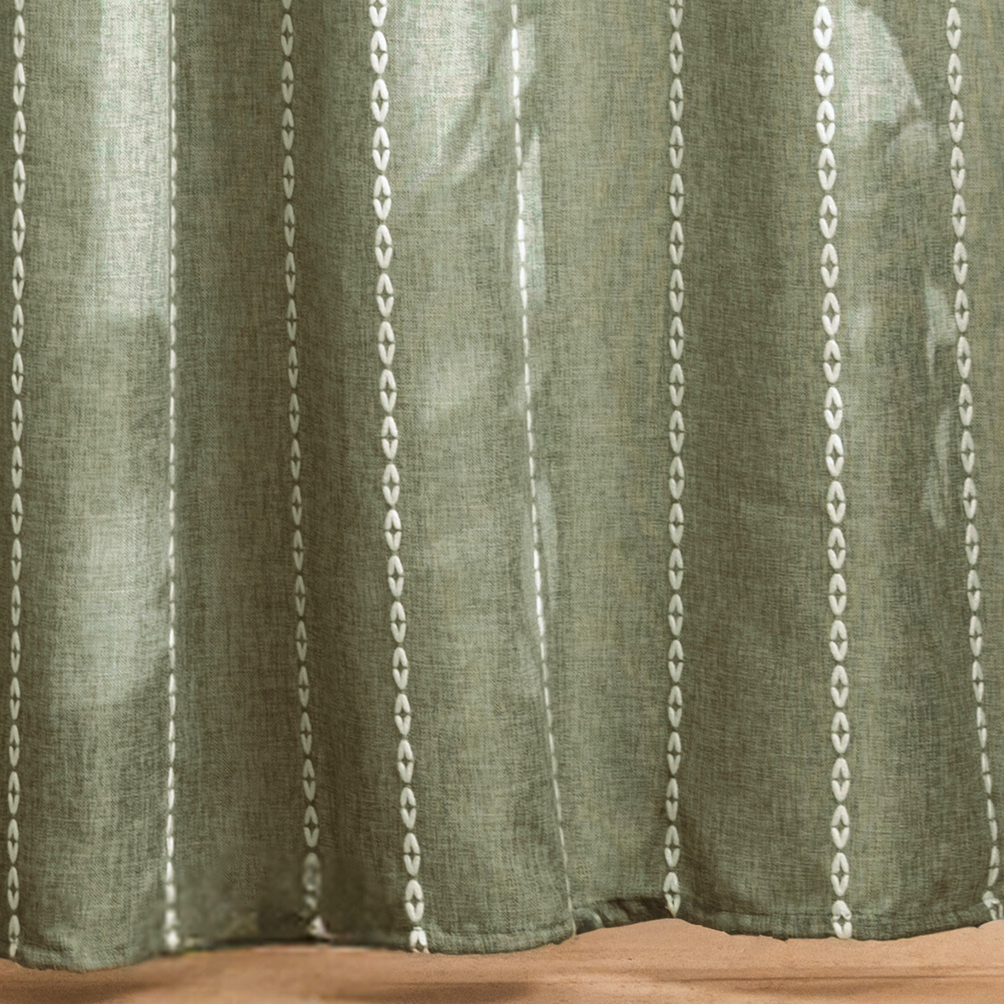 Full length sage green curtain hanging beside a white bathtub