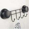 Black rack with four hooks fixed by suction cups to a tiled wall