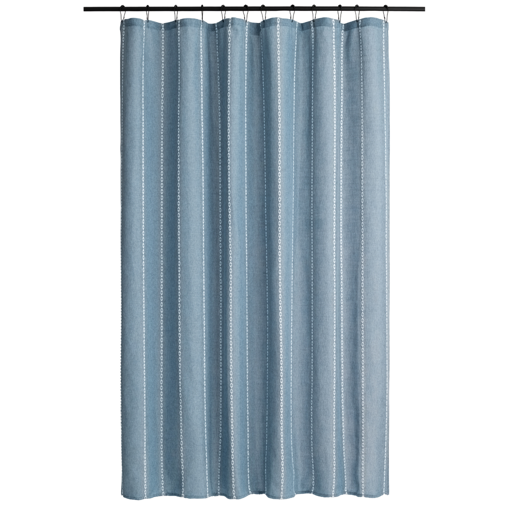 Blue grey curtain styled in a simple bathroom with pale tiling