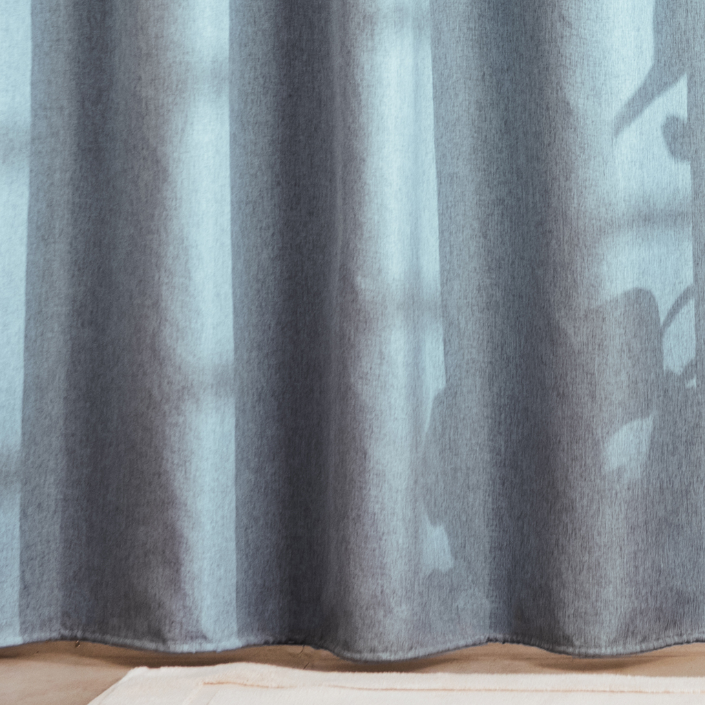 Full length powder blue curtain hanging beside a white bathtub