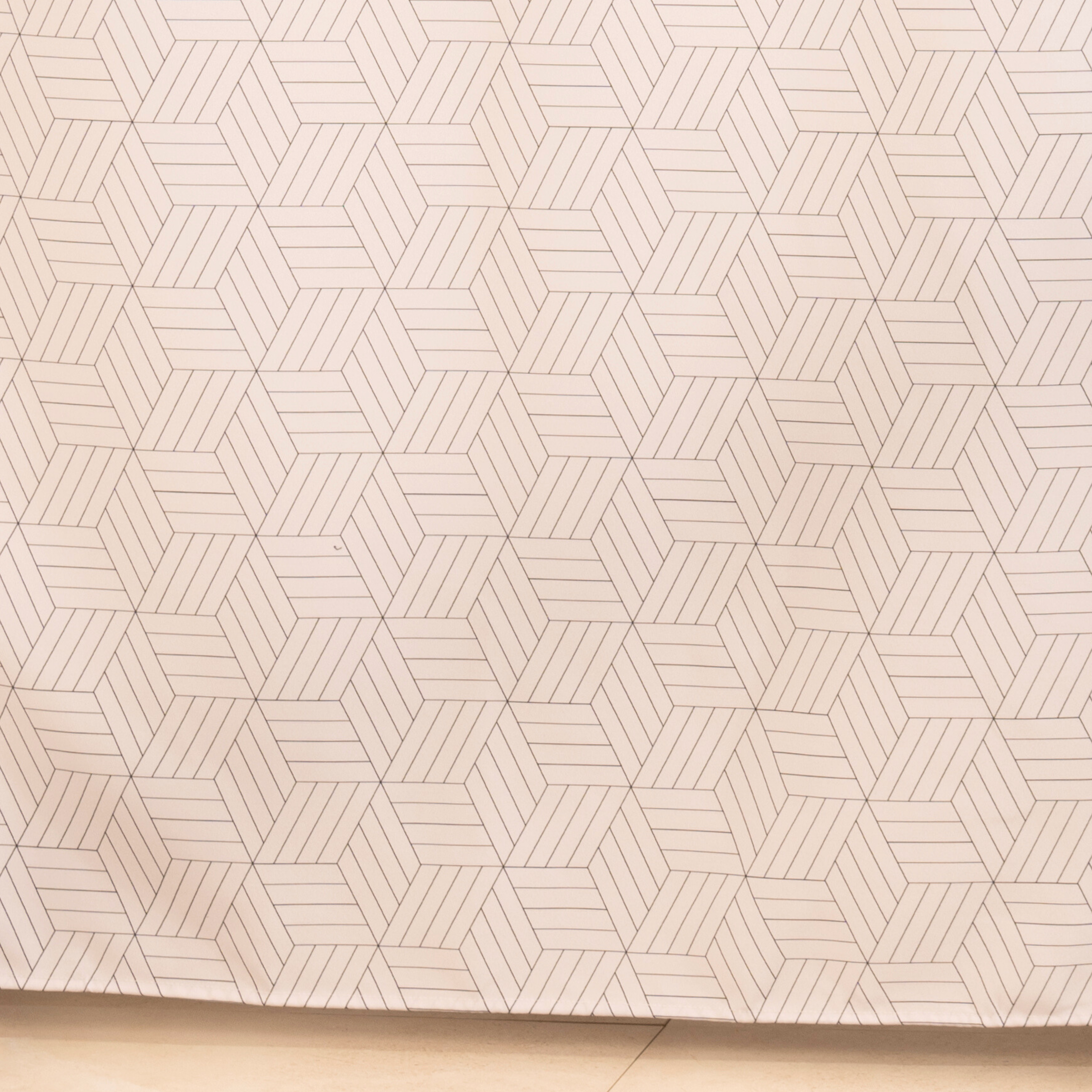 Full length cream curtain hanging beside a glass shower screen