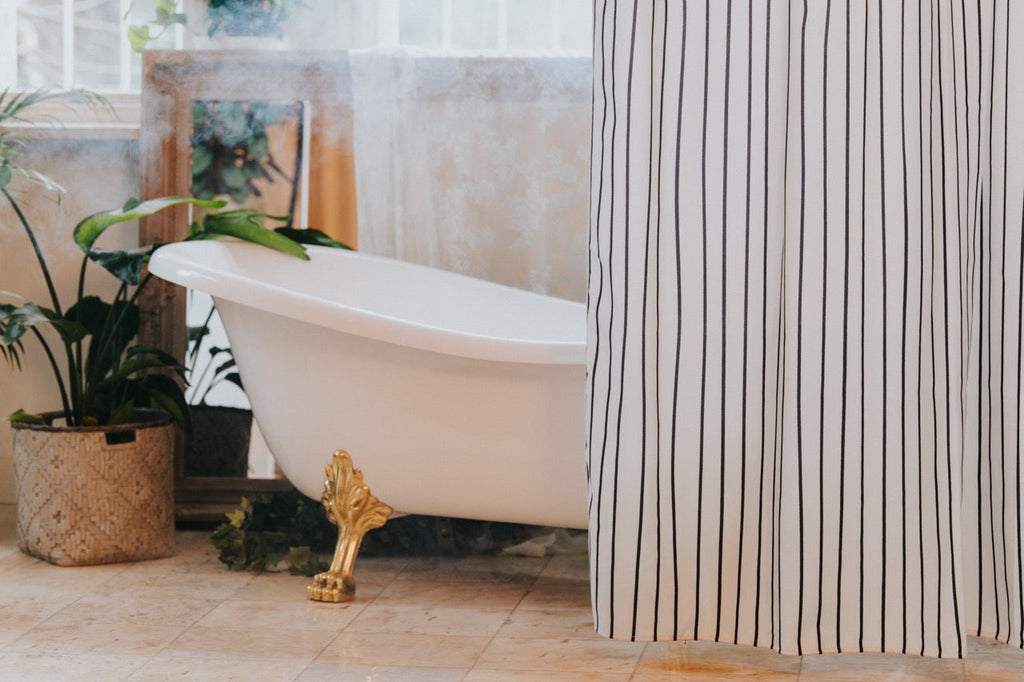 Black striped curtain styled in a bright bathroom with pale tiling