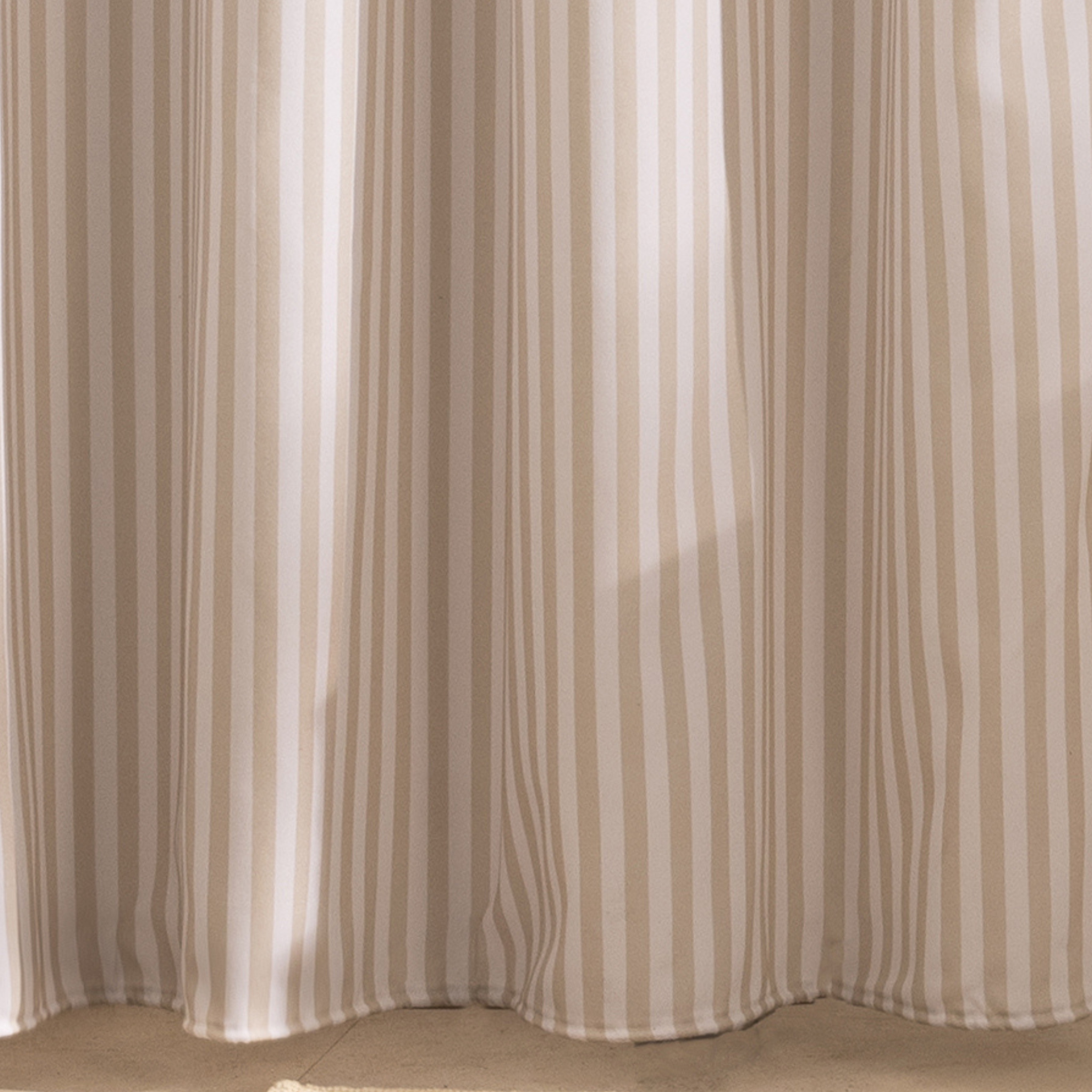 Full length beige striped curtain hanging beside a white bathtub