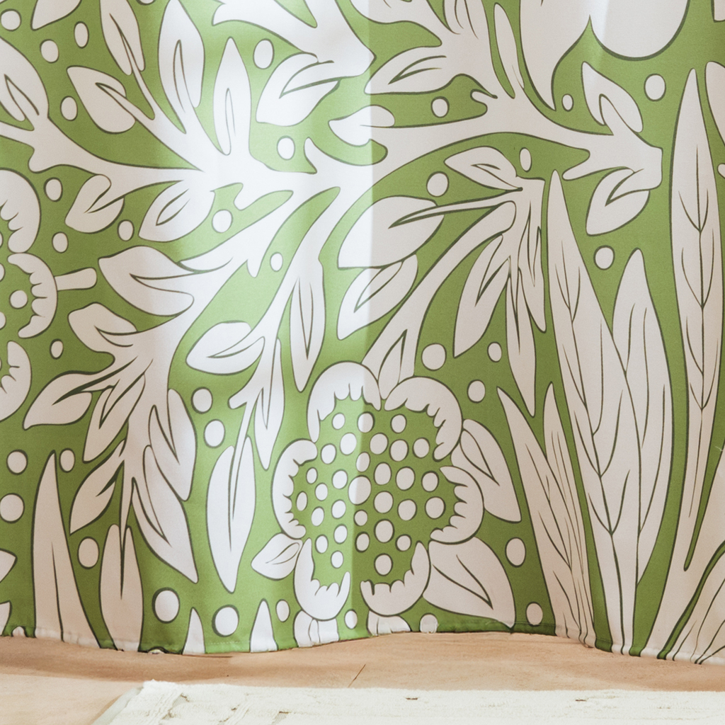 Full length botanical curtain hanging beside a glass shower screen